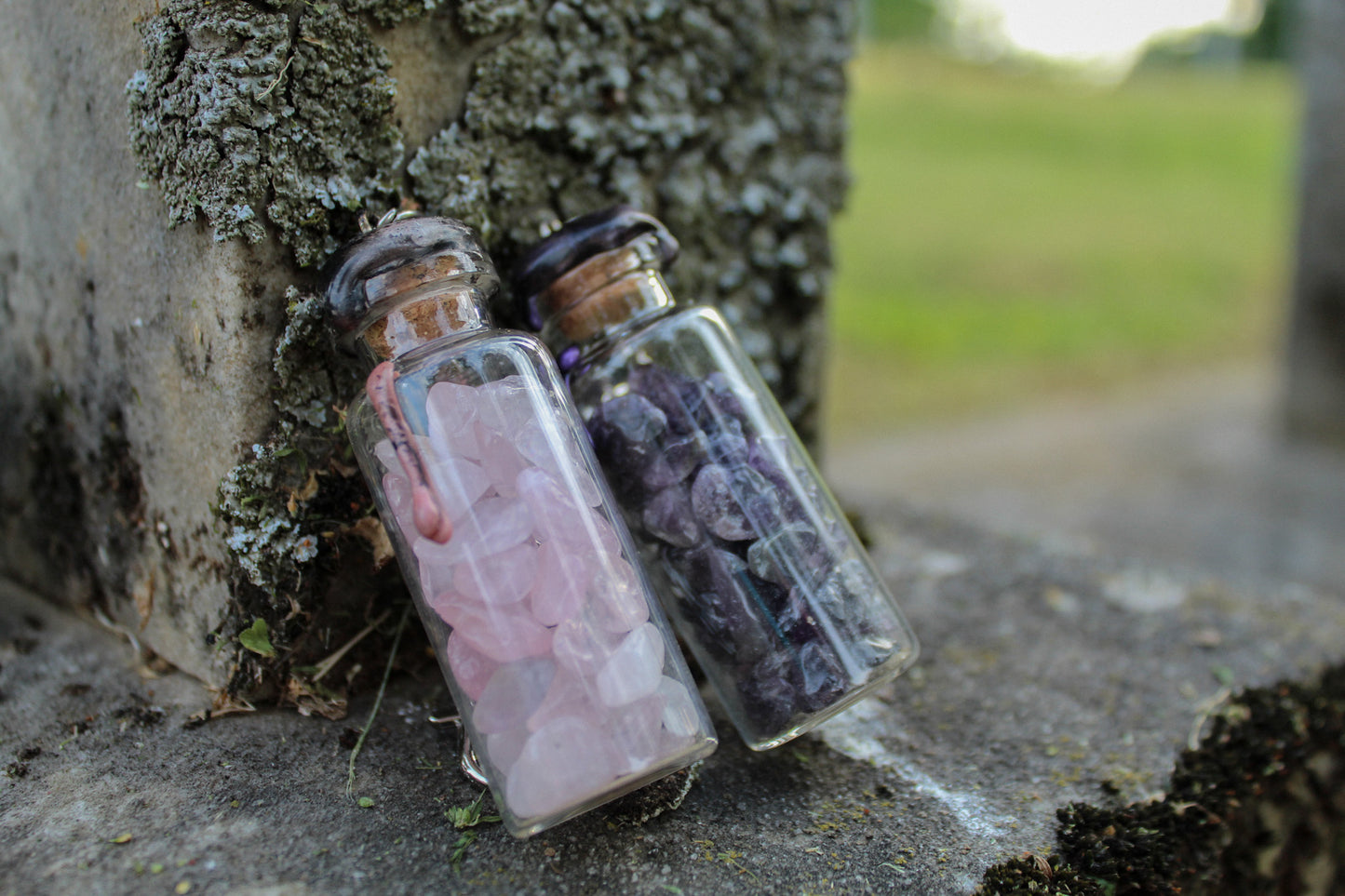 rose quartz, and amethyst crystals inside clear glass jar with wax seals and keychain attachments in front of an old tombstone